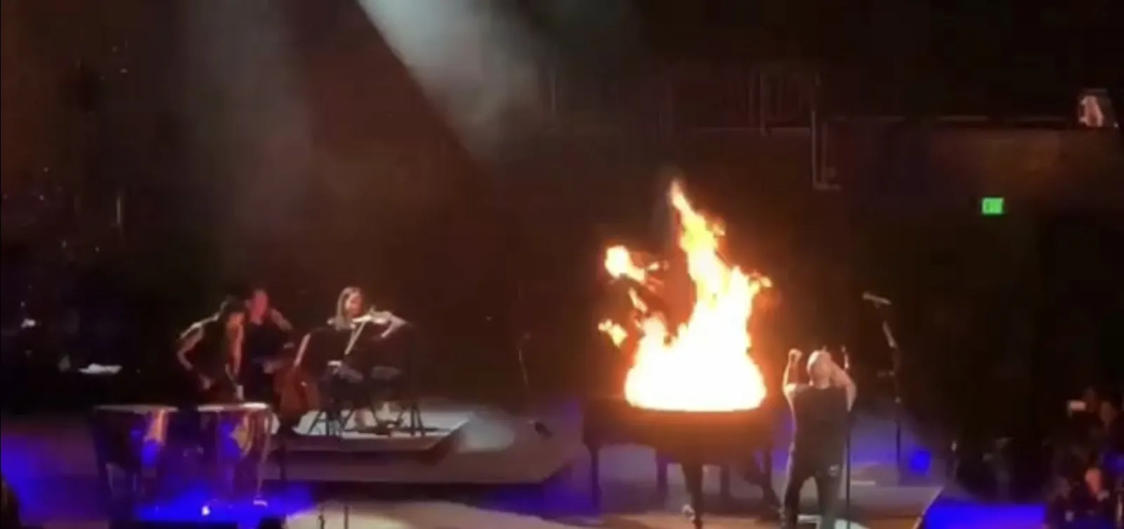 An arena performance with flames bursting above the string players